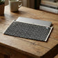 Upcycled Fabric Folder - Laptop Cover - Geometric print in black and white, featuring a secure leather strap closure